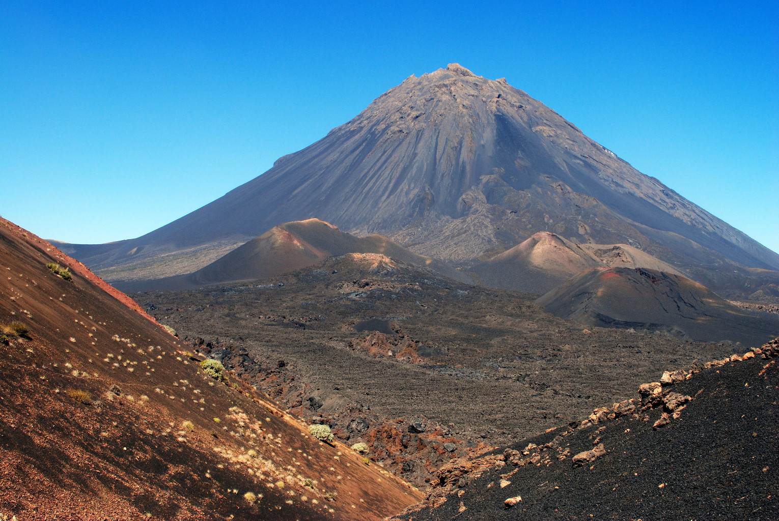 Pico do Fogo volcano rising from dark volcanic land in Cabo Verde.